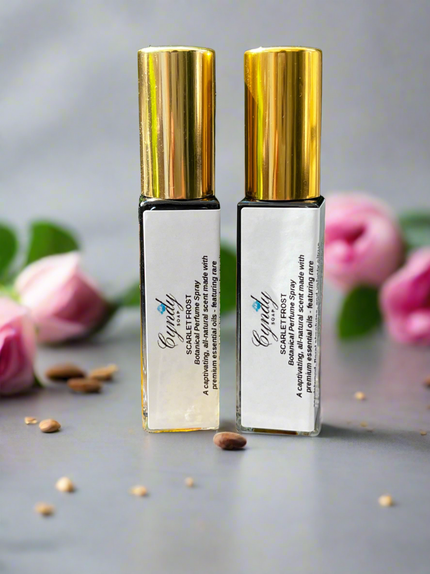 Two gold and white spray bottles with pink flowers in the background