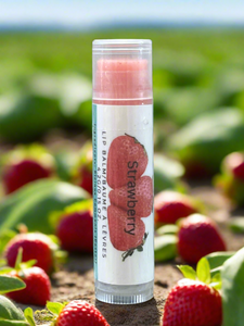 Lip balm tube labeled 'Strawberry' with strawberries in the background