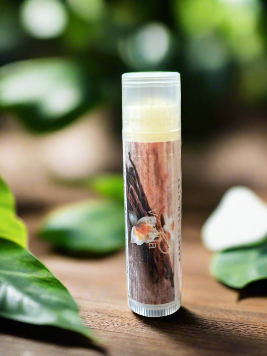Lip balm tube with a natural design on a wooden surface with green leaves in the background